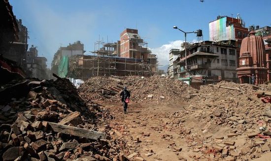 A member of Nepalese police personnel walks amidst the rubble of collapsed buildings, in the aftermath of Saturday 第1张